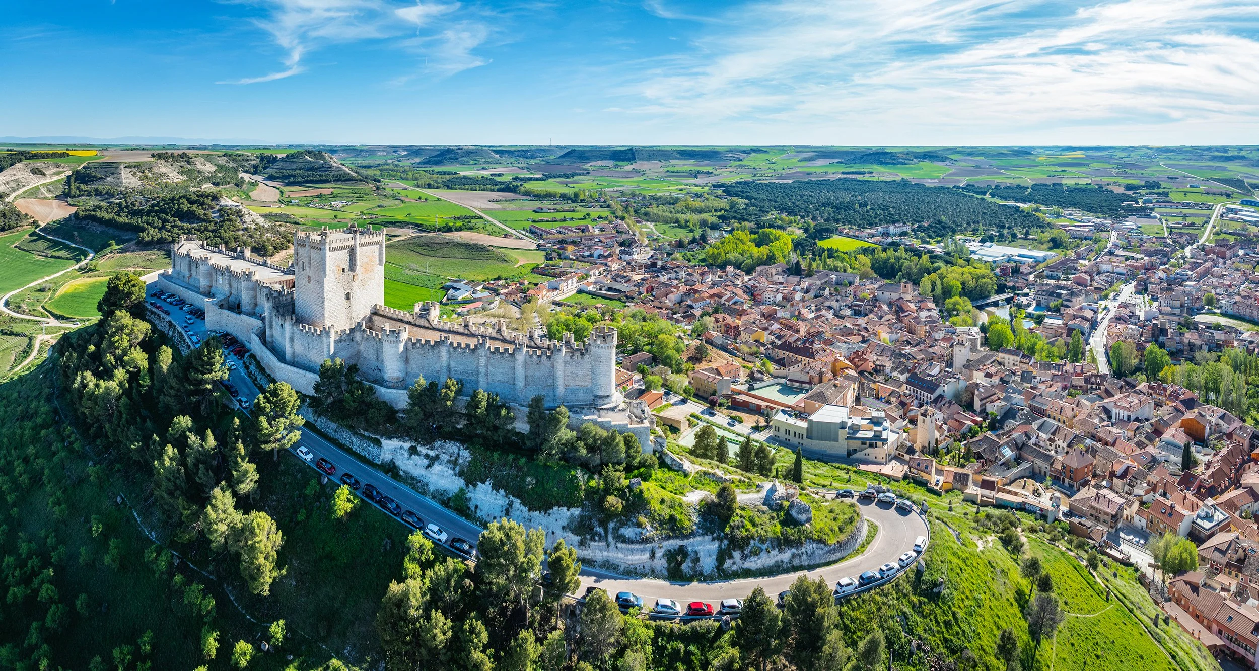 Aerial view of the famous castle of Peñafiel in Valladolid at dusk, with the old village and wine cellars in the background.