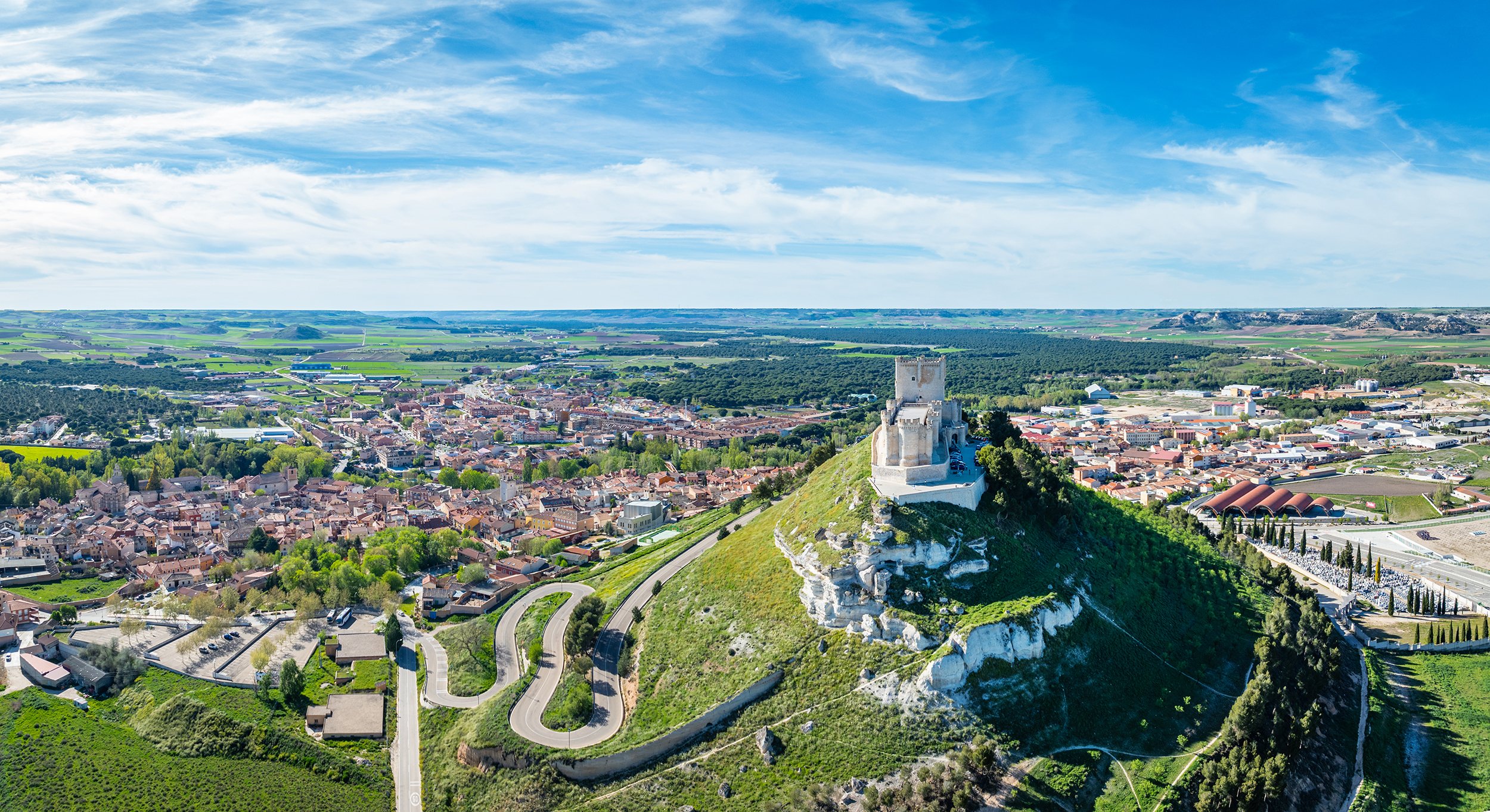 Aerial view of the famous castle of Peñafiel in Valladolid at dusk, with the old village and wine cellars in the background.