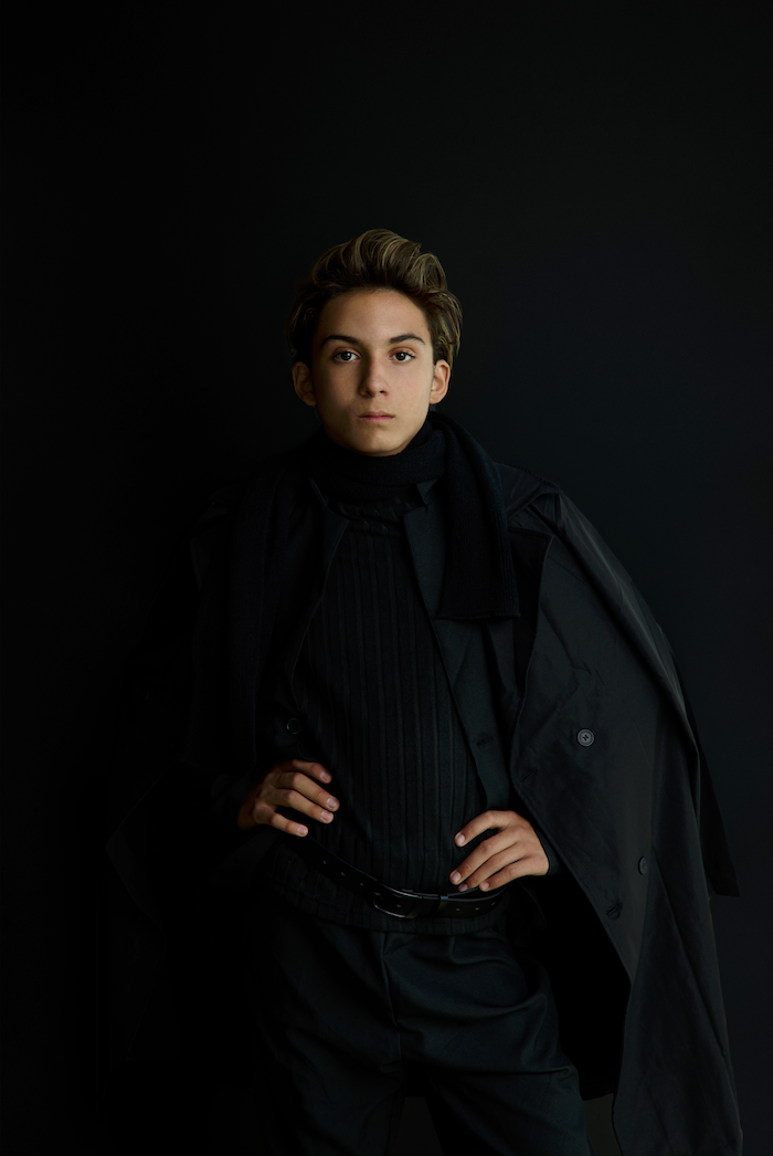 dark background studio portrait of a young man looking into the camera with a fashionable wardrobe