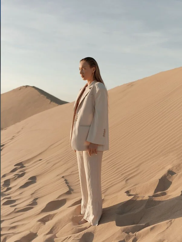 Woman in a white suit standing on a sand dune