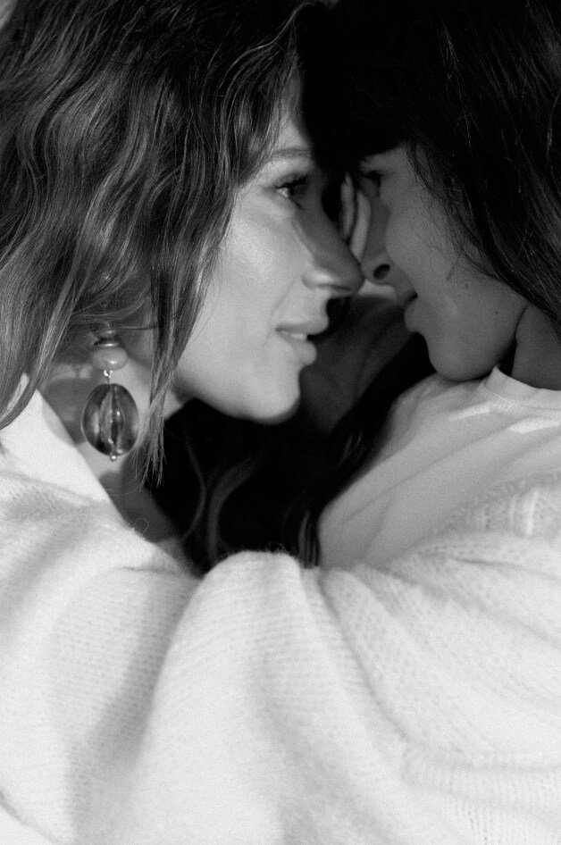 Two women with close faces, touching foreheads and noses, in an intimate pose.
