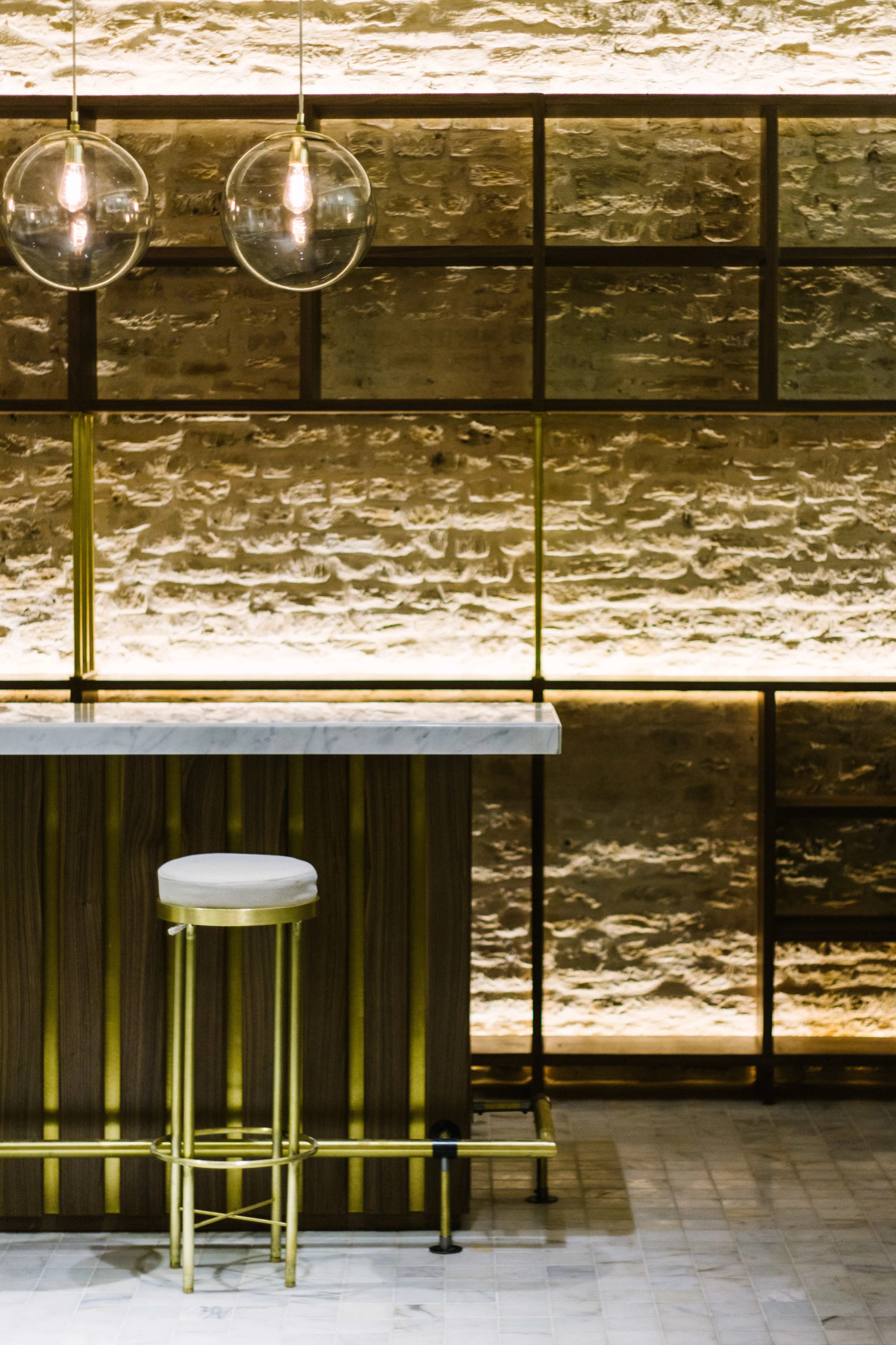 The bar was crafted in walnut wood with bronze accents and a marble tabletop, photo by Santiago Marzola .