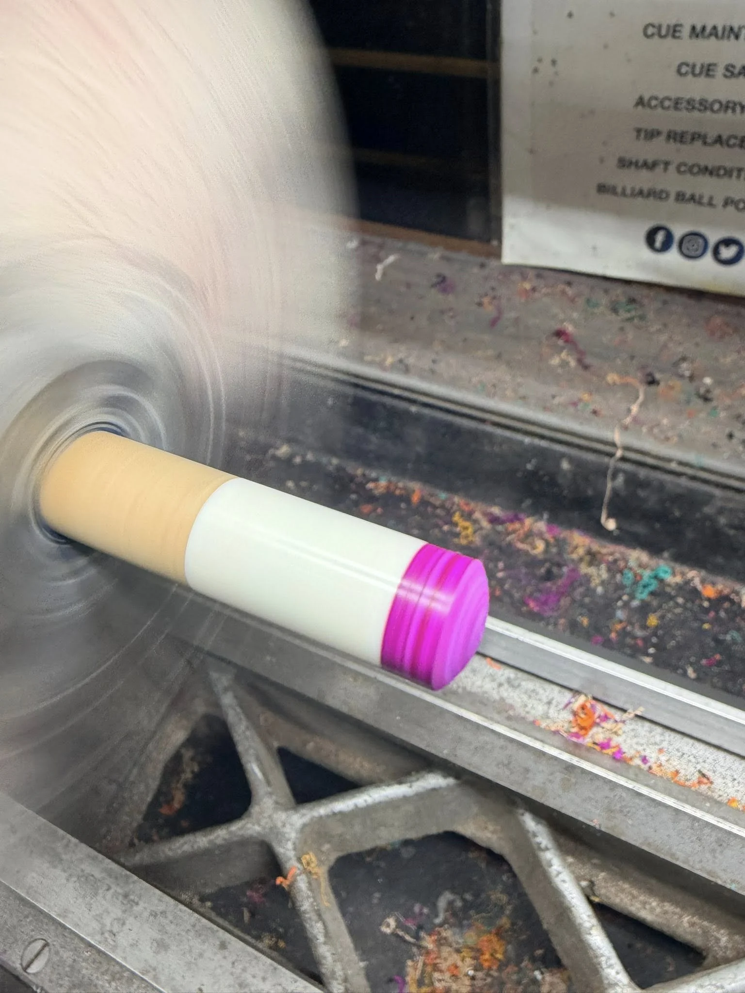 A cue shaft spinning on the lathe during a tip installation