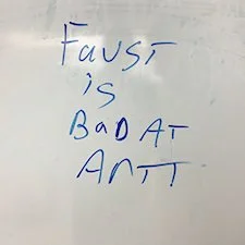 Whiteboard with the handwritten message 'FausT is BAD AT ANT'.
