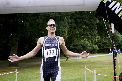  Male Windrush athlete running across the finishing line 