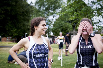  Two Windrush athletes in club kit looking happy and relieved after just finishing the race 