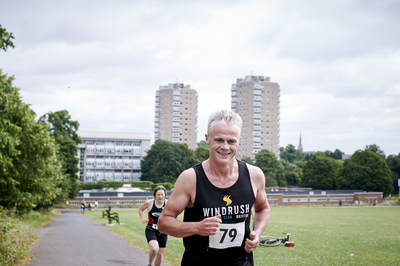  Male competitor wearing aquathlon t-shirt running in Brockwell park 