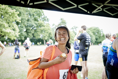  Smiling female competitor enjoying a piece of cake after aquathlon 