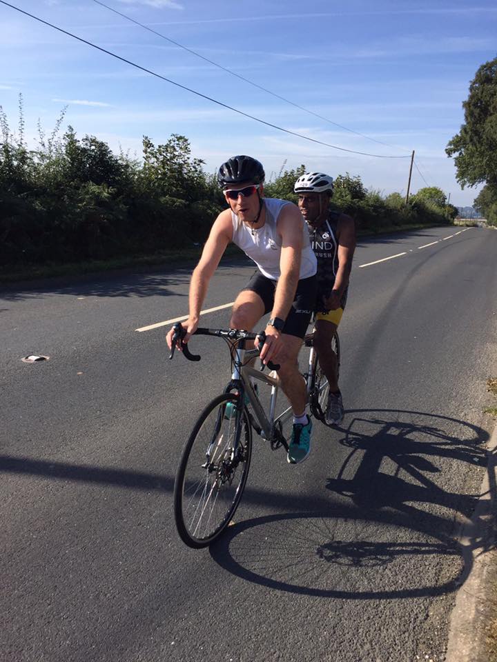  Two male triathletes road cycling on tandem bike during race 