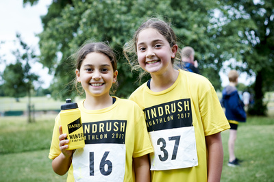 Two smiling girls in the park wearing yellow windrush aquathlon tshirts 