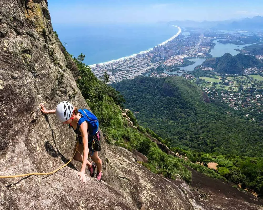 Rock climber finishing the first pitch of the route Passagem dos Olhos on Pedra da Gavea