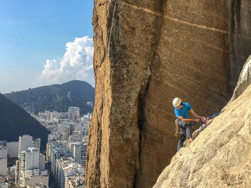 Rock climber at the top a chimney climb on Morro do Cantagalo in Rio de Janeiro