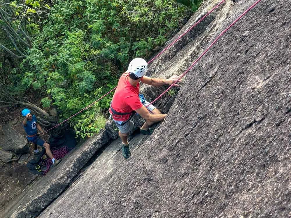 Student climbing a dihedral during his rock climbing lesson