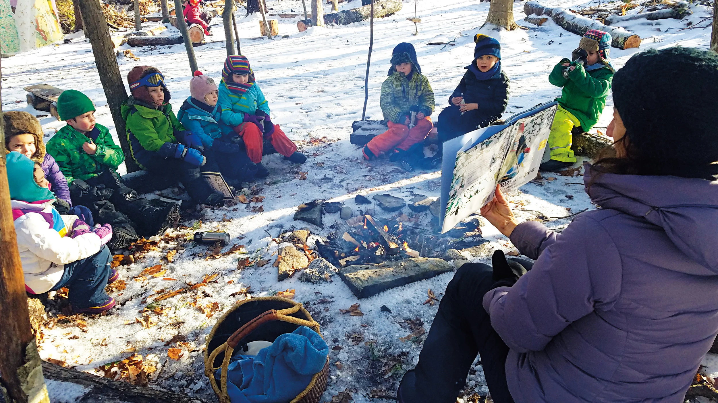 Anne Stires ‘94 reads to nature preschool and kindergarten students in the Salamander Woods outdoor classroom.