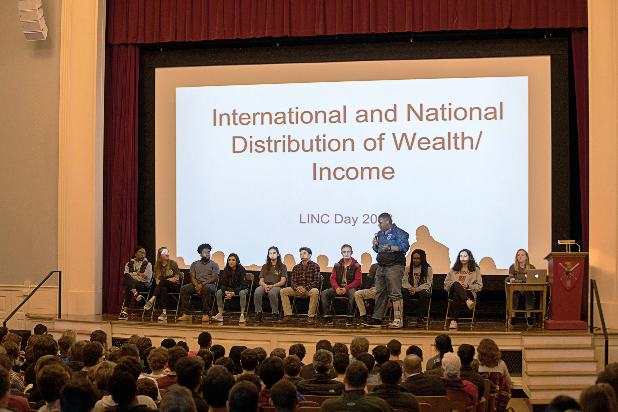 Above Keith Dean ’19 explains to students wealth distribution as it relates to the School population. T op right Dean asks students to take a seat under the economic bracket that best represents them.