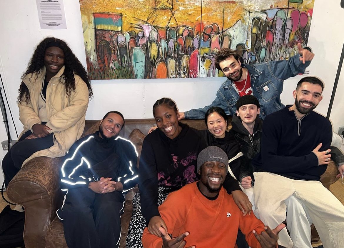  A group of young creatives are sat on the couch, smiling at the camera. 