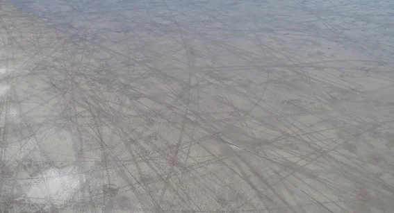 Cycle tracks and footprints on water-covered concrete.