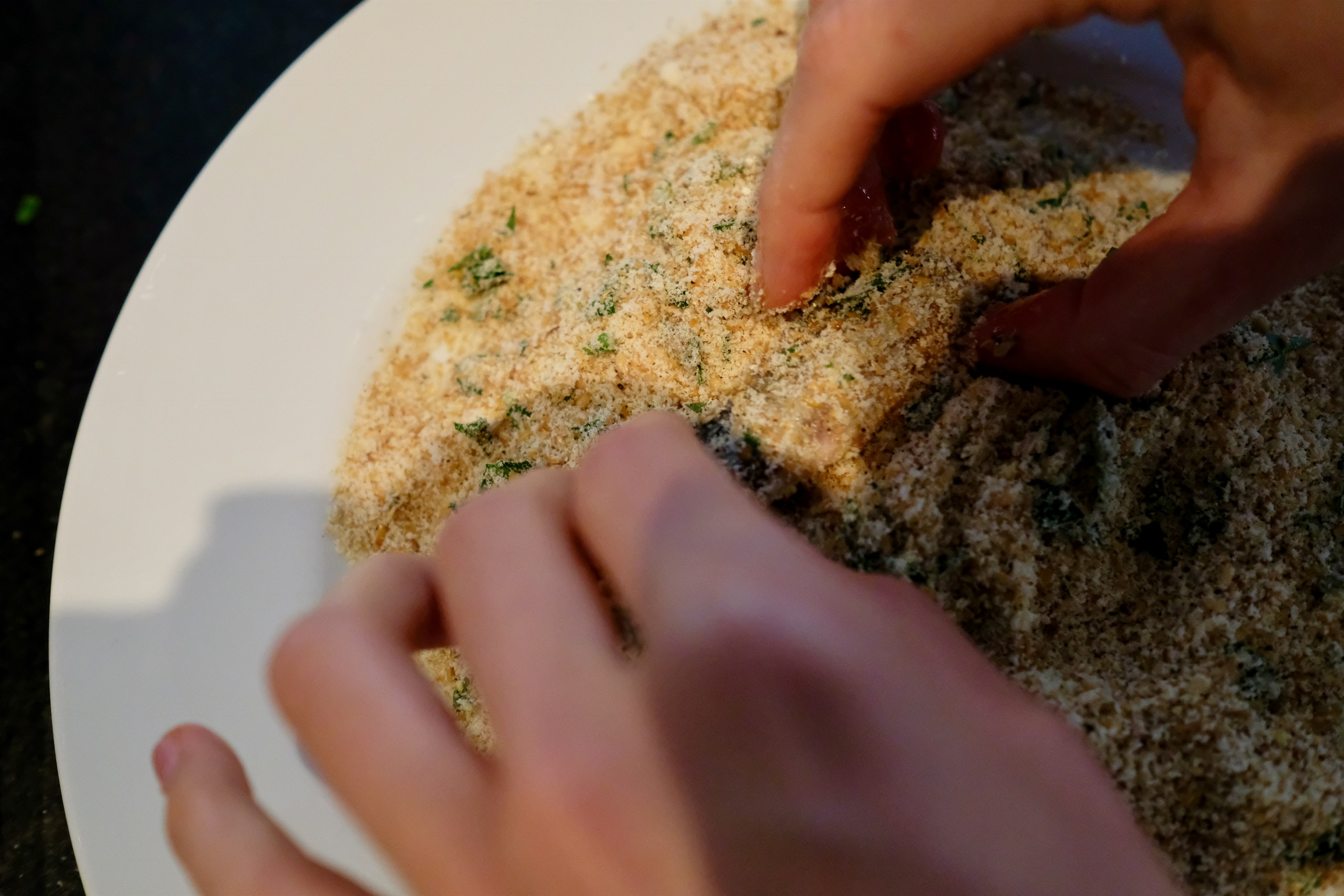 Coating the egg-covered sardine in the breadcrumb mixture