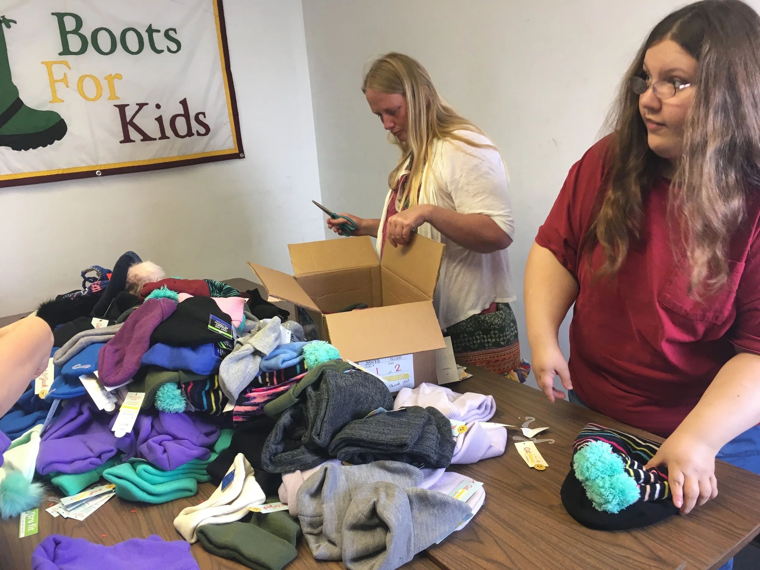 Erin, left, and Kristi sort through hats and mittens.