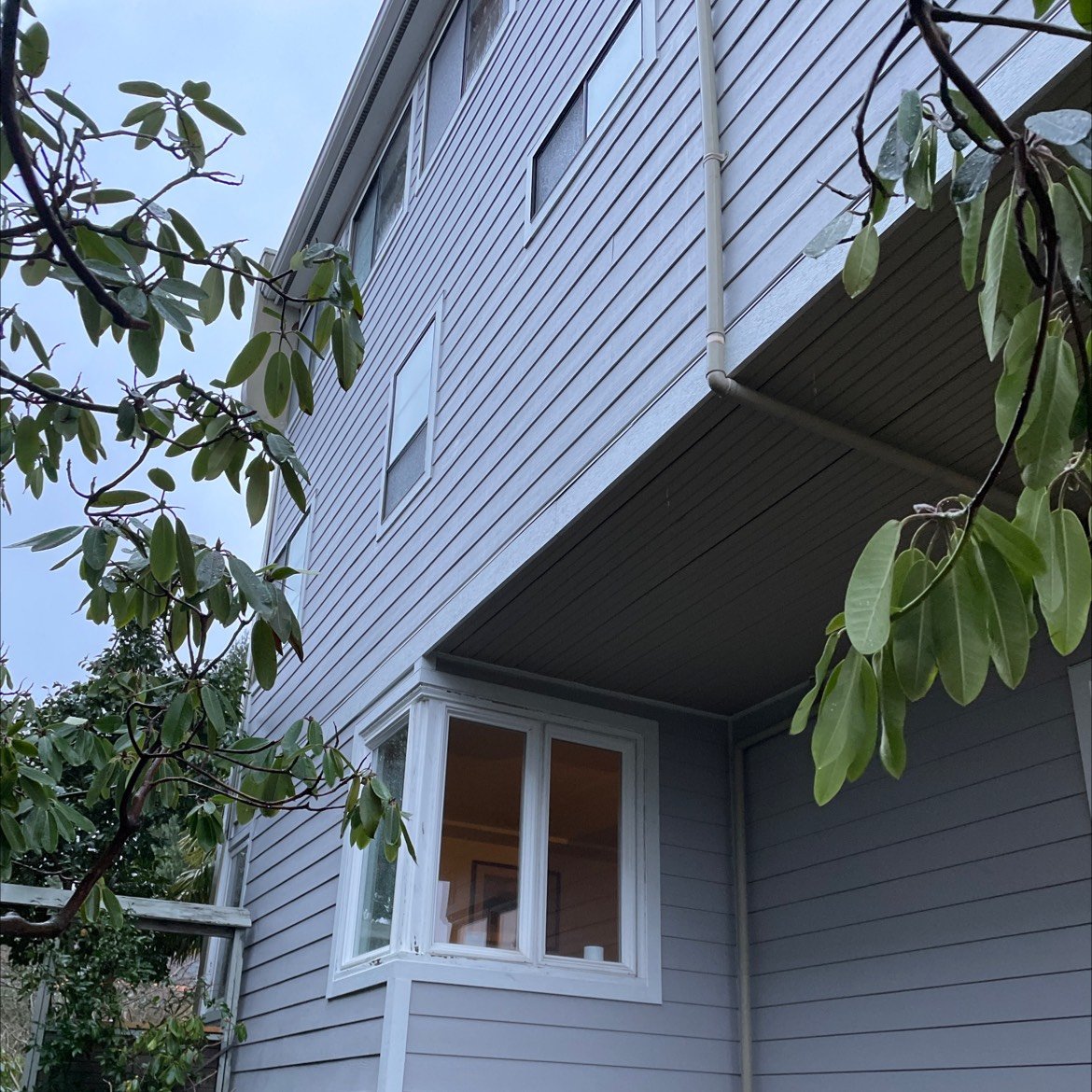 Three-story home with light gray horizontal lap siding and white-trimmed windows, illustrating a vertical view of quality siding installation and exterior detailing.