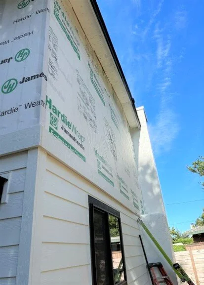 Home exterior in progress with HardieWrap weather barrier and partially installed fiber cement siding, showing professional siding installation using James Hardie materials.
