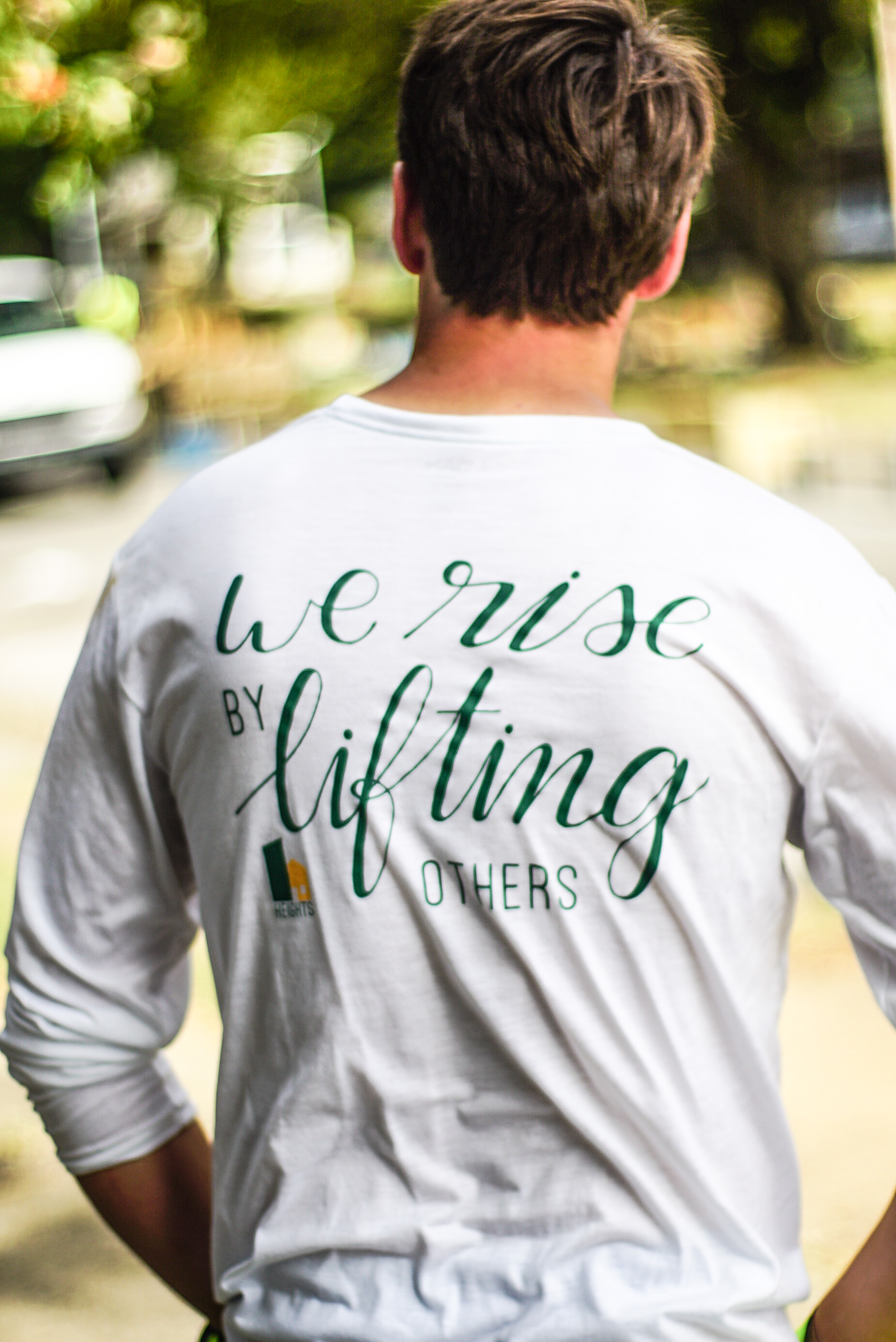 back of t-shirt that reads "we rise by lifting others"