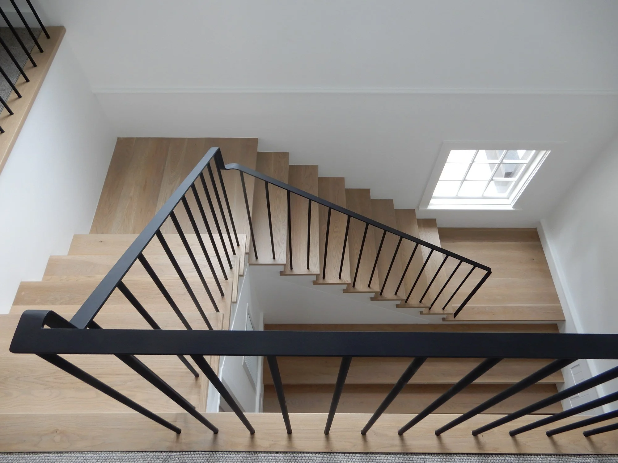  Looking down an oak staircase with black powder-coated steel balustrade and a skylight, Northern Beaches 