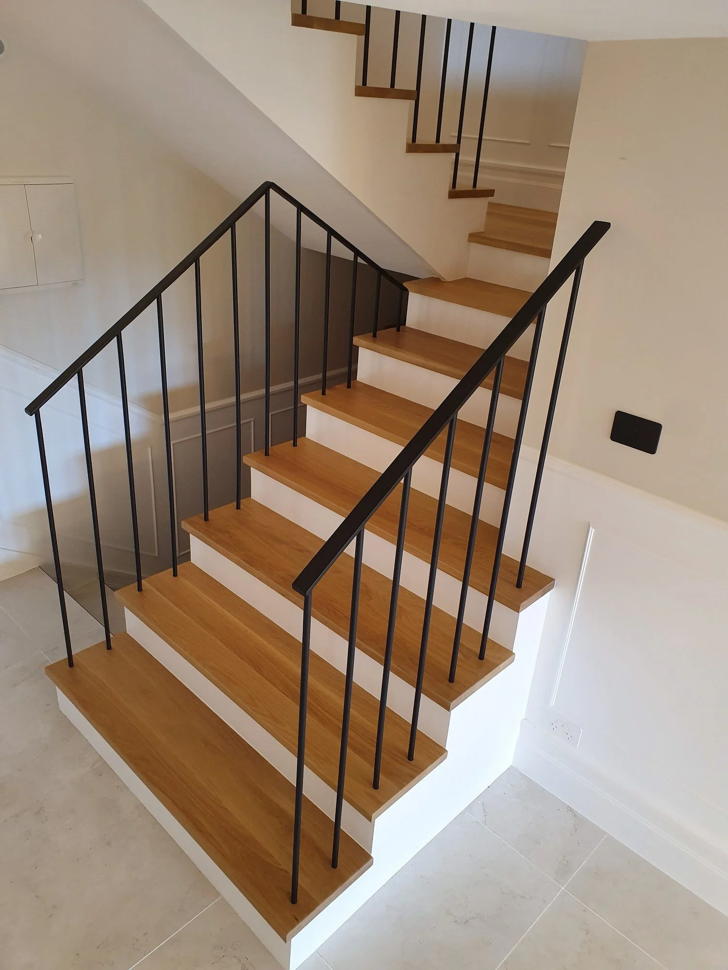  Black steel rod balusters on an oak-tread staircase with white risers and panelled walls, North Sydney 