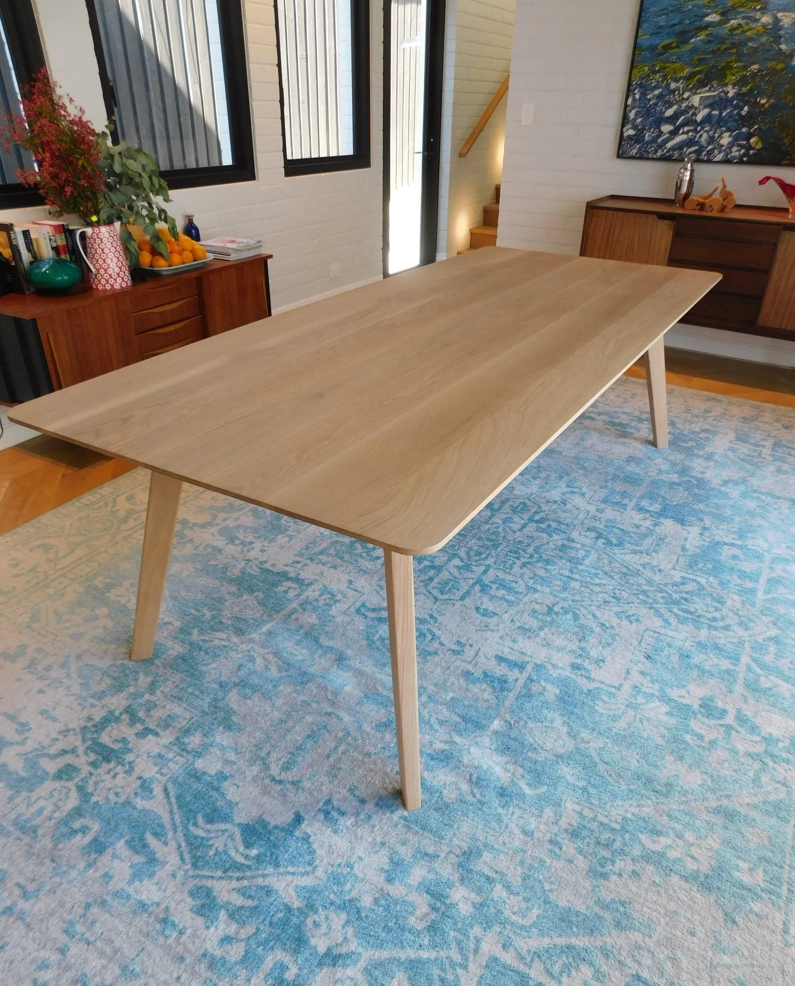  Custom oak dining table with tapered splayed legs on a blue patterned rug, made in Sydney 