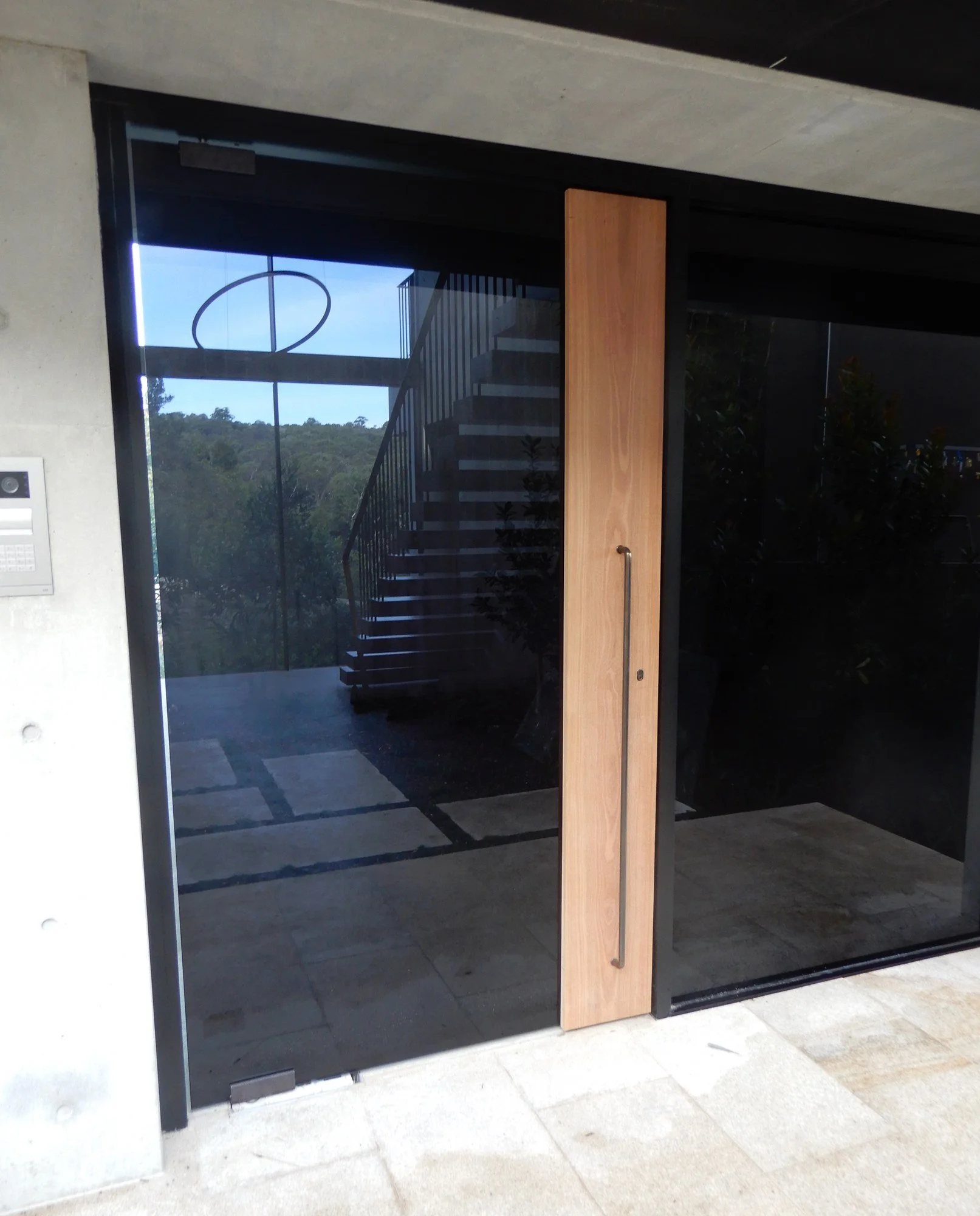  Full-height timber pull panel with steel handle on a black-framed glass entry door, Northern Beaches 