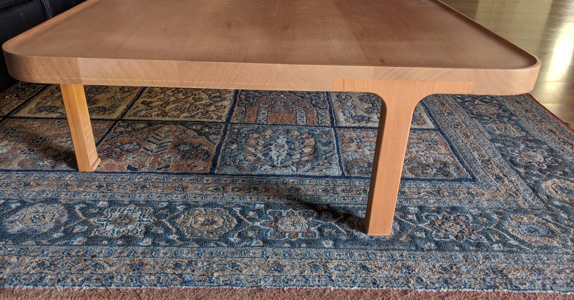  Low timber coffee table with a raised rounded lip around the top, on a patterned rug, Sydney 