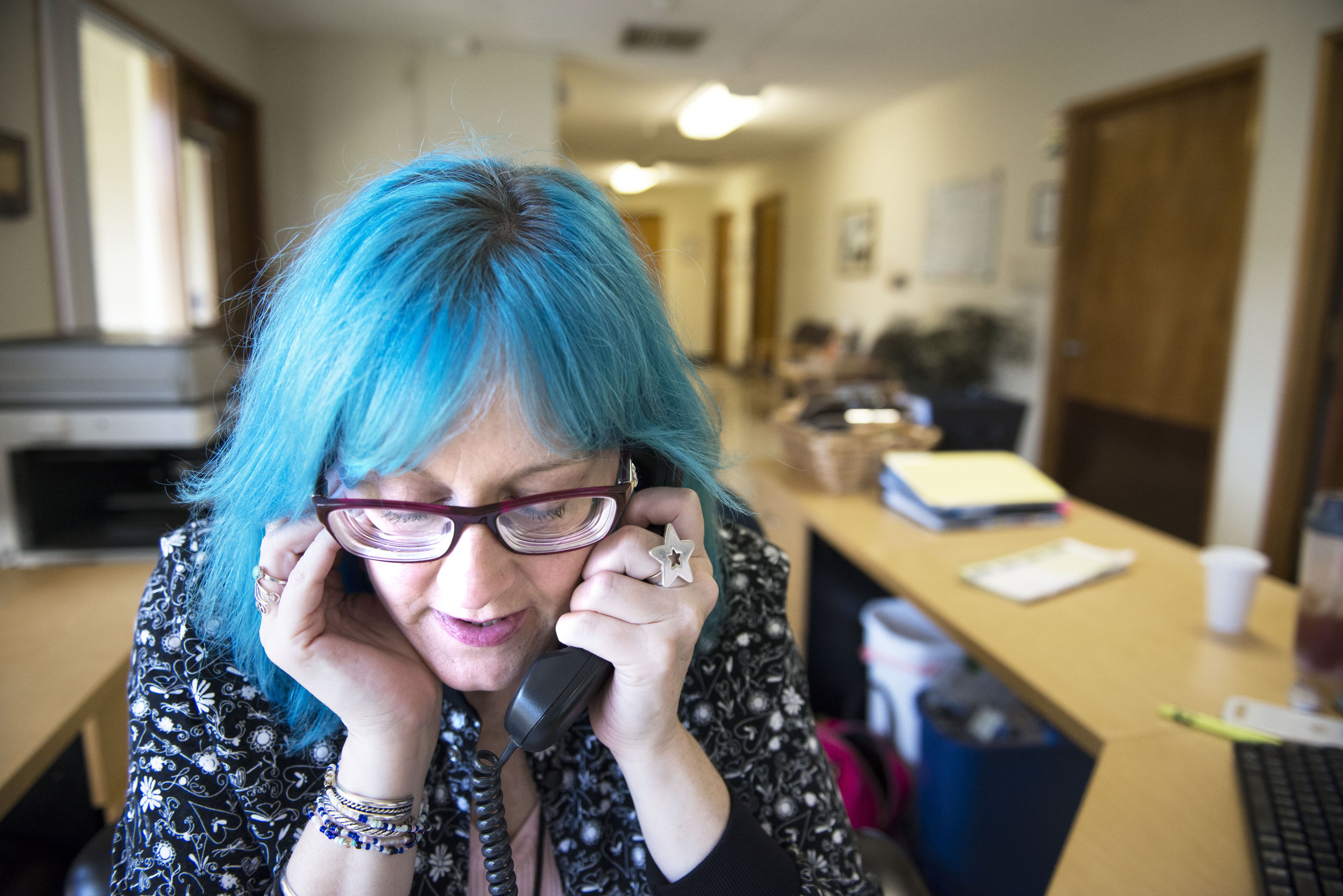  Timberly Eyssen plugs her ear to better hear a phone call while confirming patient appointments during her volunteer job at Battleground Health Care on Friday, July 6, 2018. Eyssen began volunteering at the clinic after she said they helped her with