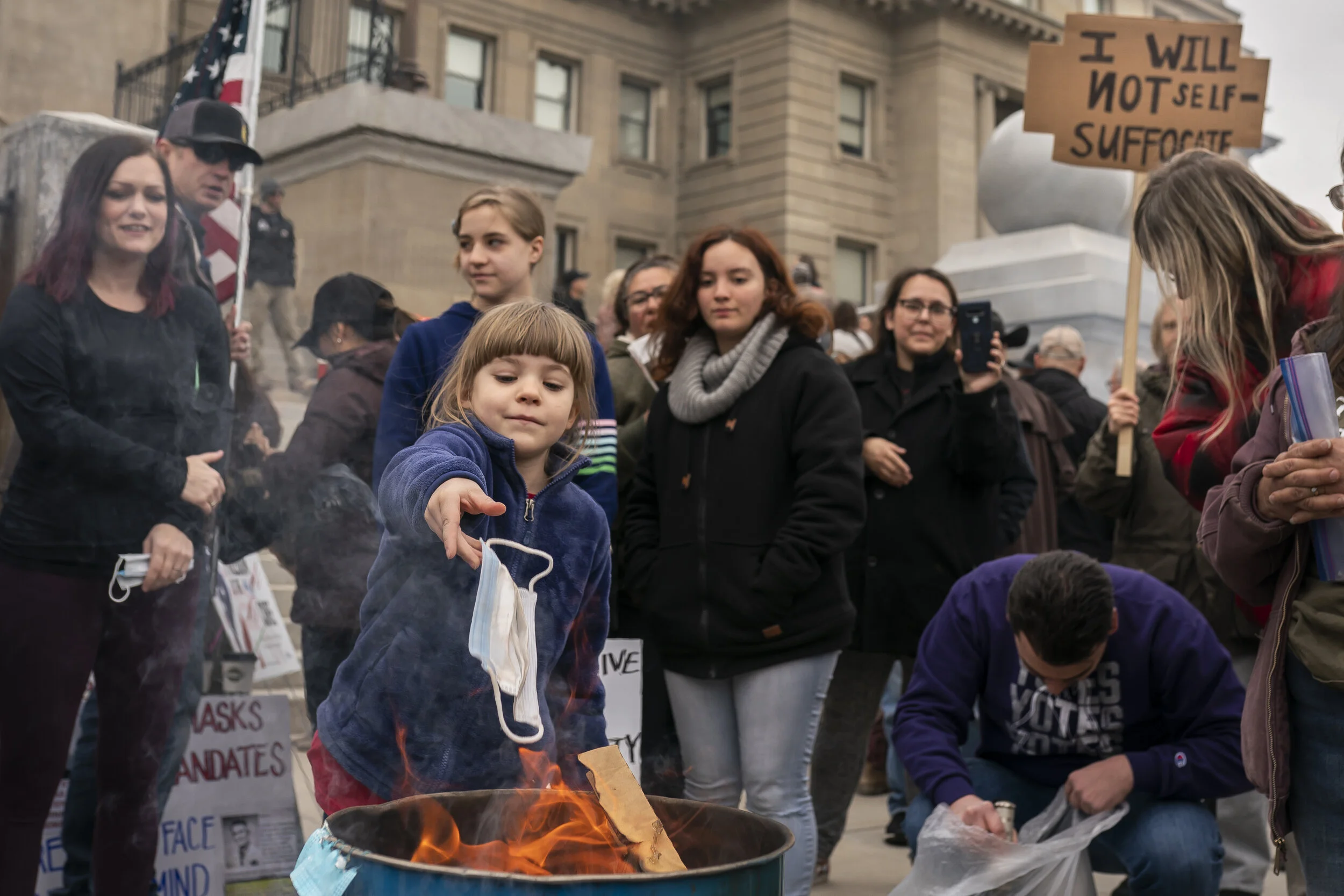  A child tosses a surgical mask into a fire during a mask burning event at the Idaho Statehouse on March 6, 2021 in Boise, Idaho. Citizens and politicians, including Lieutenant Governor Janice McGeachin, gathered in at least 20 cities across the stat