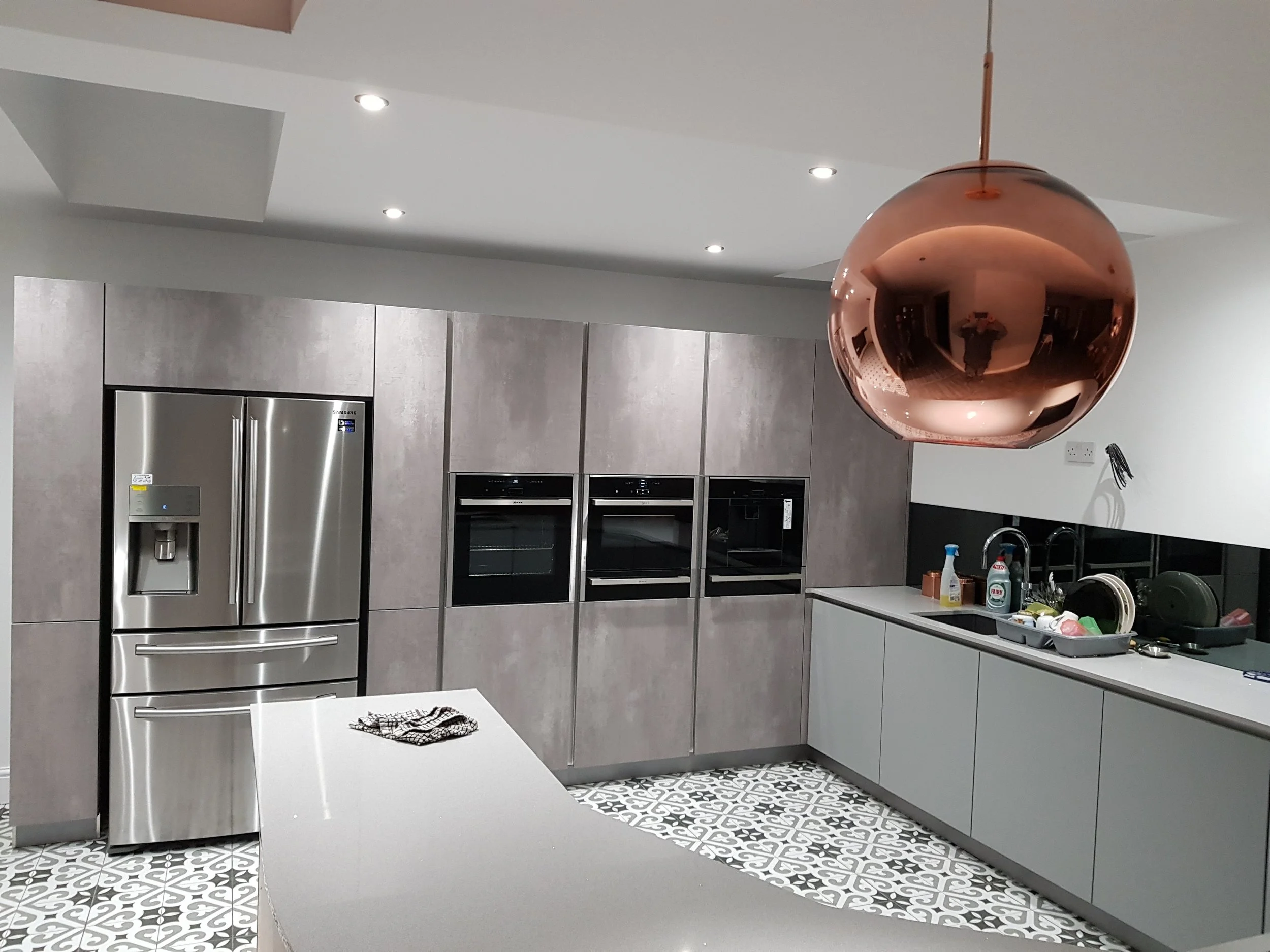 Tall units are in putty concrete laminate, with pearl grey matt lacquer base units. The copper lights are lovely touch, chosen by Emma.