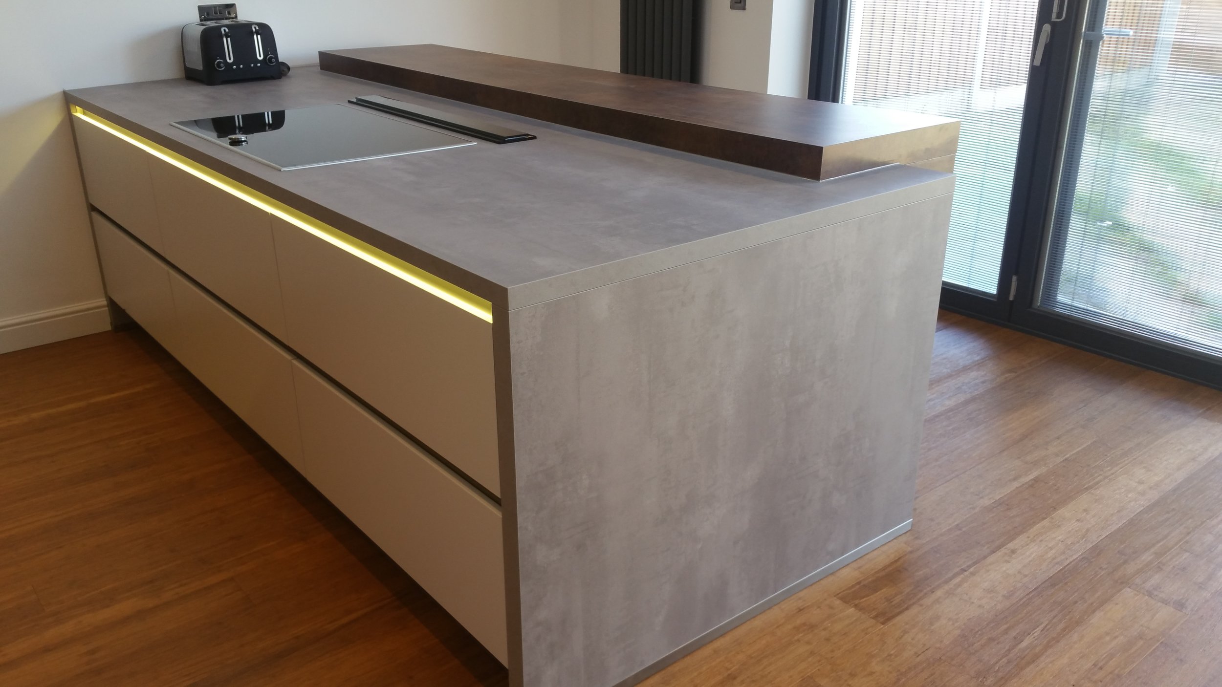 Here's one of our recent installations. The concrete style laminate worktop wraps round the drawer units, and a contrasting copper coloured laminate forms the breakfast bar area at the rear.