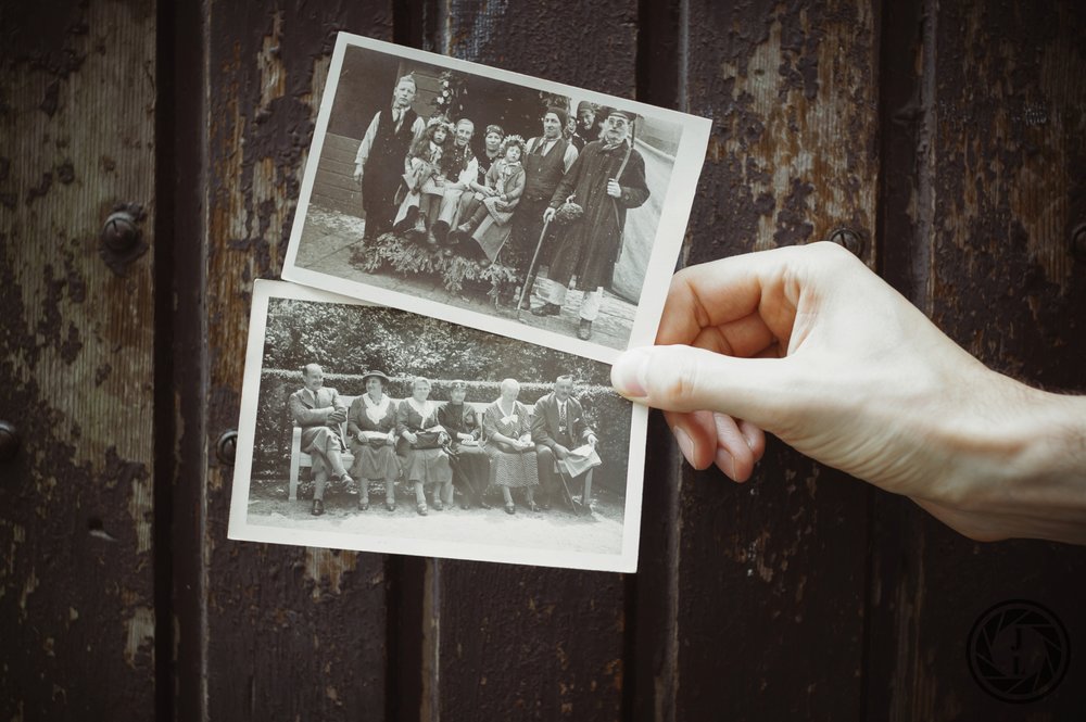  image of a hand holding two black and white pictures of older families&nbsp; 