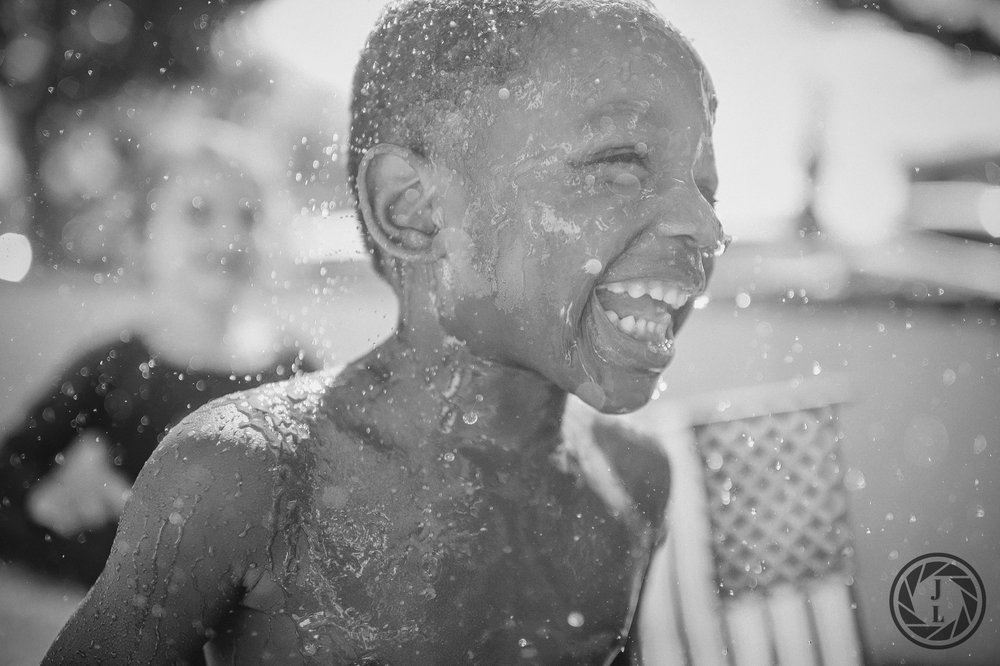  image of a yong boy laughing as water is splashed all over him 