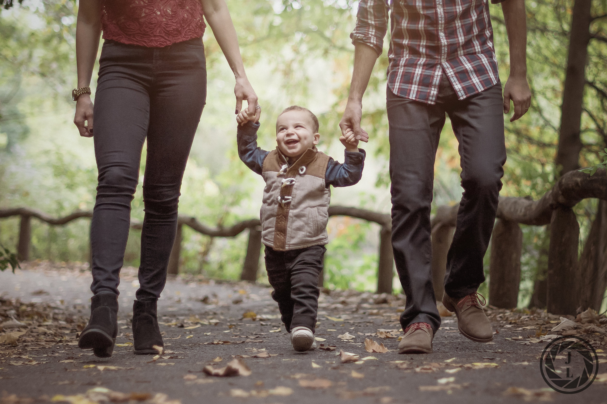 A happy, smiling toddler holding hands and walking with parents.