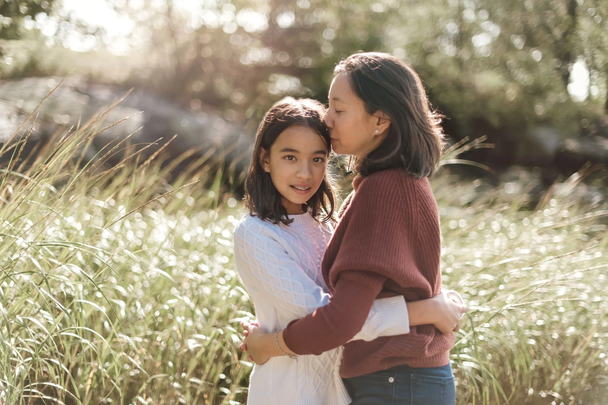 A mother embracing her two children while they look at the camera.