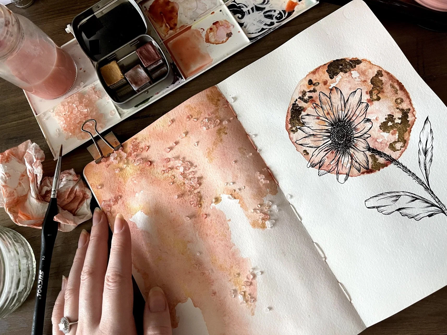 Sketchbook spread filled with textured watercolour using a salt method