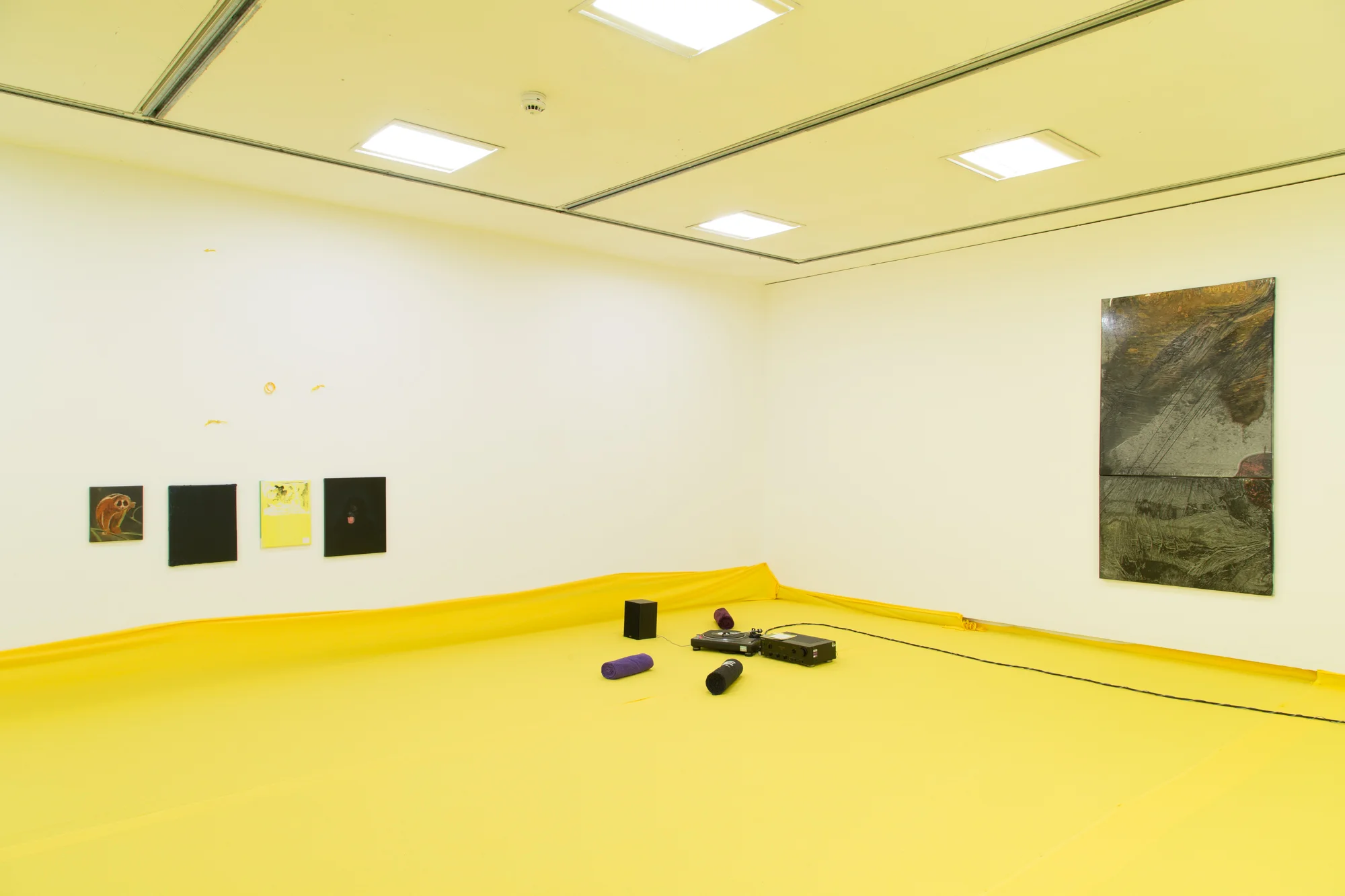 Installation view of 'Do U Feel Like We Do? at Intermedia Gallery, CCA Glasgow 2014. (Cotton, X-frame, photographic background, studio lights, towels, oil paint, turntable, amplifier, speakers, silicon gel bracelets, screws, inkjet prints, coins, plaster and video paint.) Photo: Tom Nolan