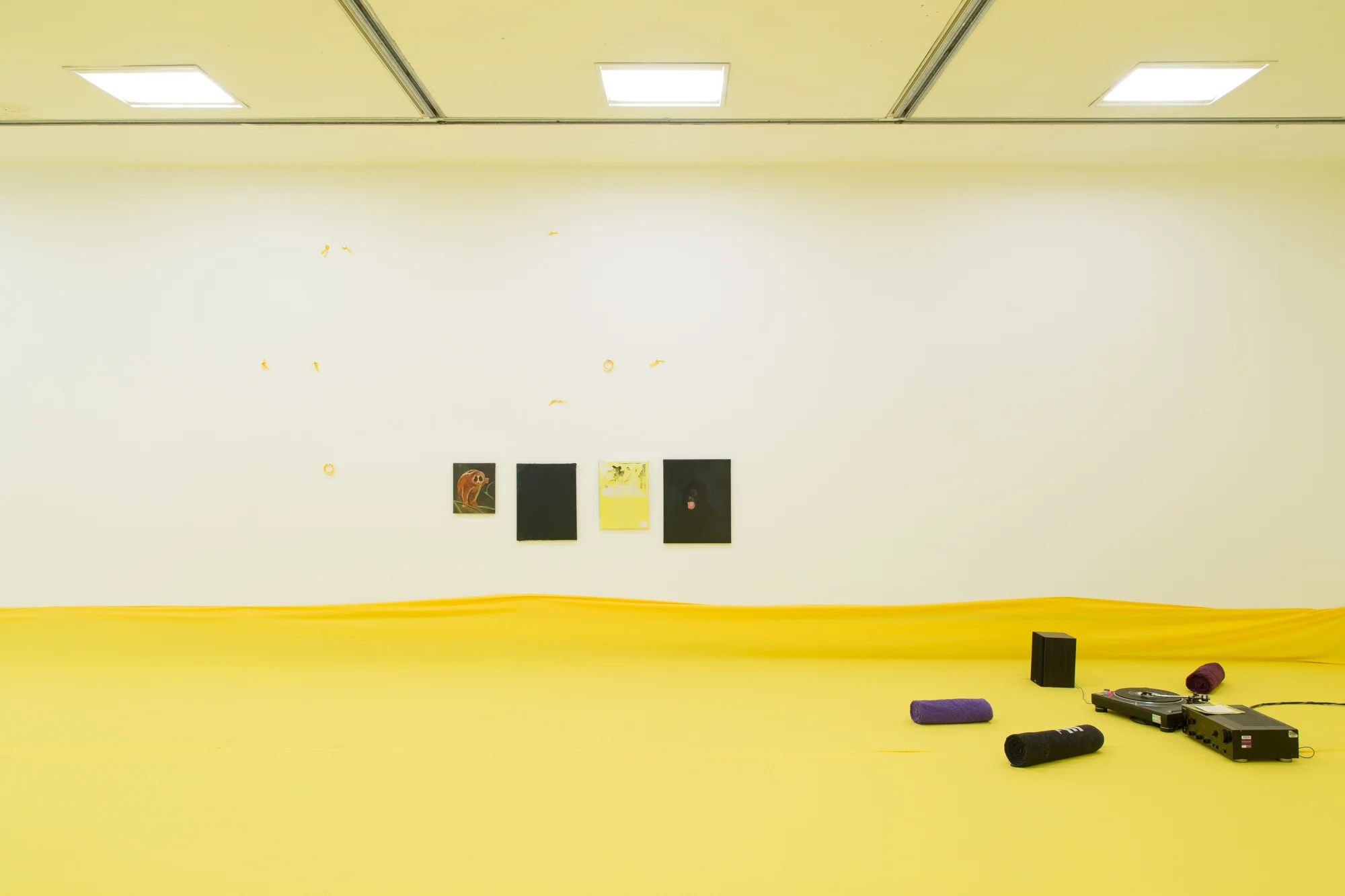 Installation view of 'Do U Feel Like We Do? at Intermedia Gallery, CCA Glasgow 2014. (Cotton, X-frame, photographic background, studio lights, towels, oil paint, turntable, amplifier, speakers, silicon gel bracelets, screws, inkjet prints, coins, plaster and video paint.) Photo: Tom Nolan