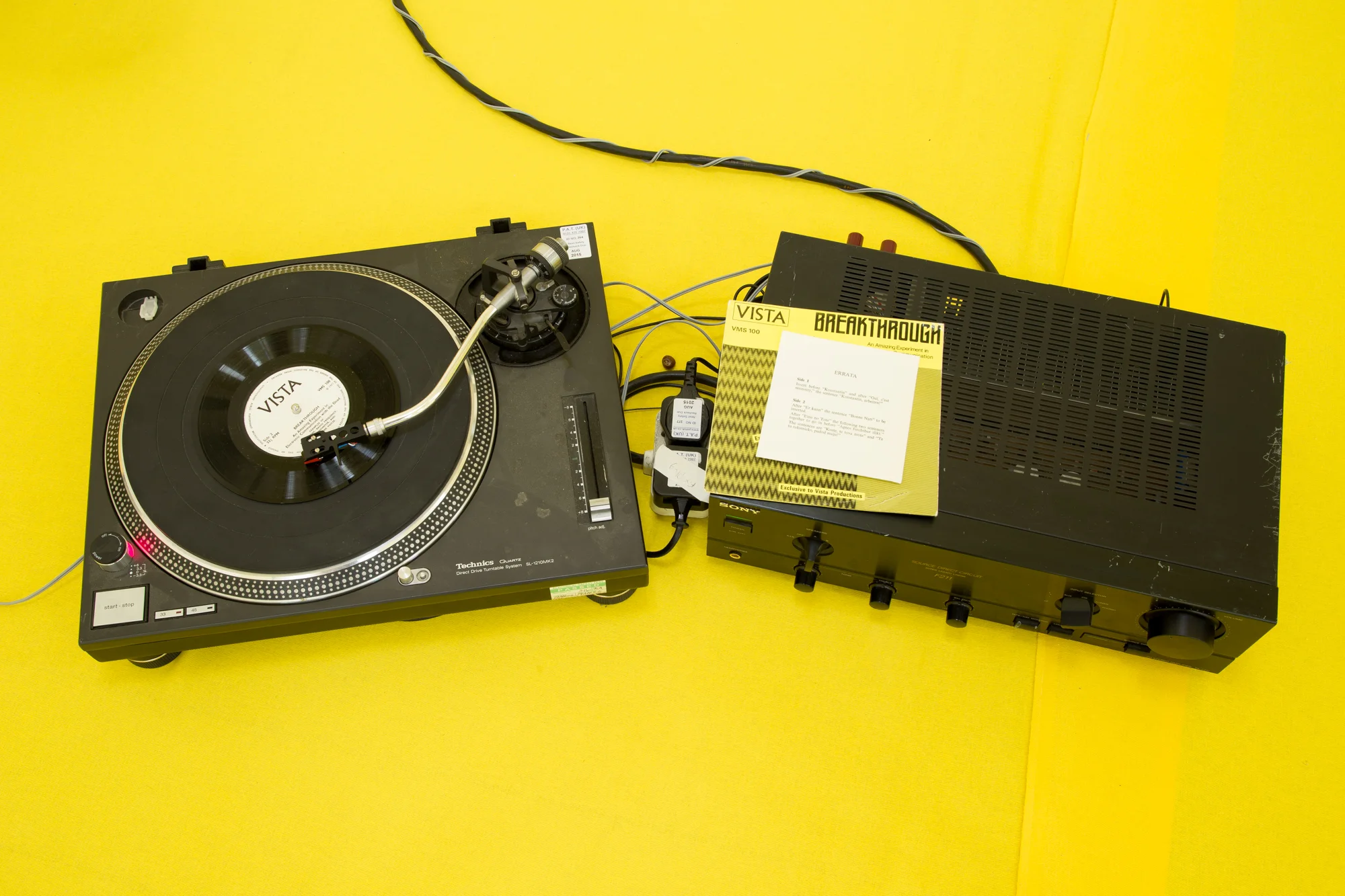 Installation view of 'Do U Feel Like We Do? at Intermedia Gallery, CCA Glasgow 2014. (Cotton, X-frame, photographic background, studio lights, towels, oil paint, turntable, amplifier, speakers, silicon gel bracelets, screws, inkjet prints, coins, plaster and video paint.) Photo: Tom Nolan