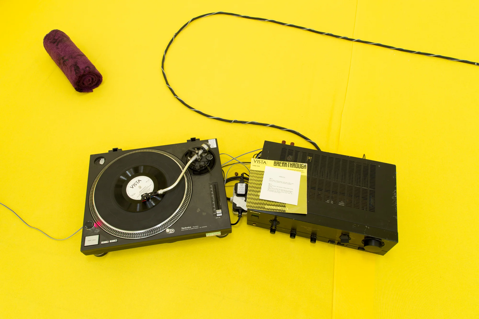 Installation view of 'Do U Feel Like We Do? at Intermedia Gallery, CCA Glasgow 2014. (Cotton, X-frame, photographic background, studio lights, towels, oil paint, turntable, amplifier, speakers, silicon gel bracelets, screws, inkjet prints, coins, plaster and video paint.) Photo: Tom Nolan