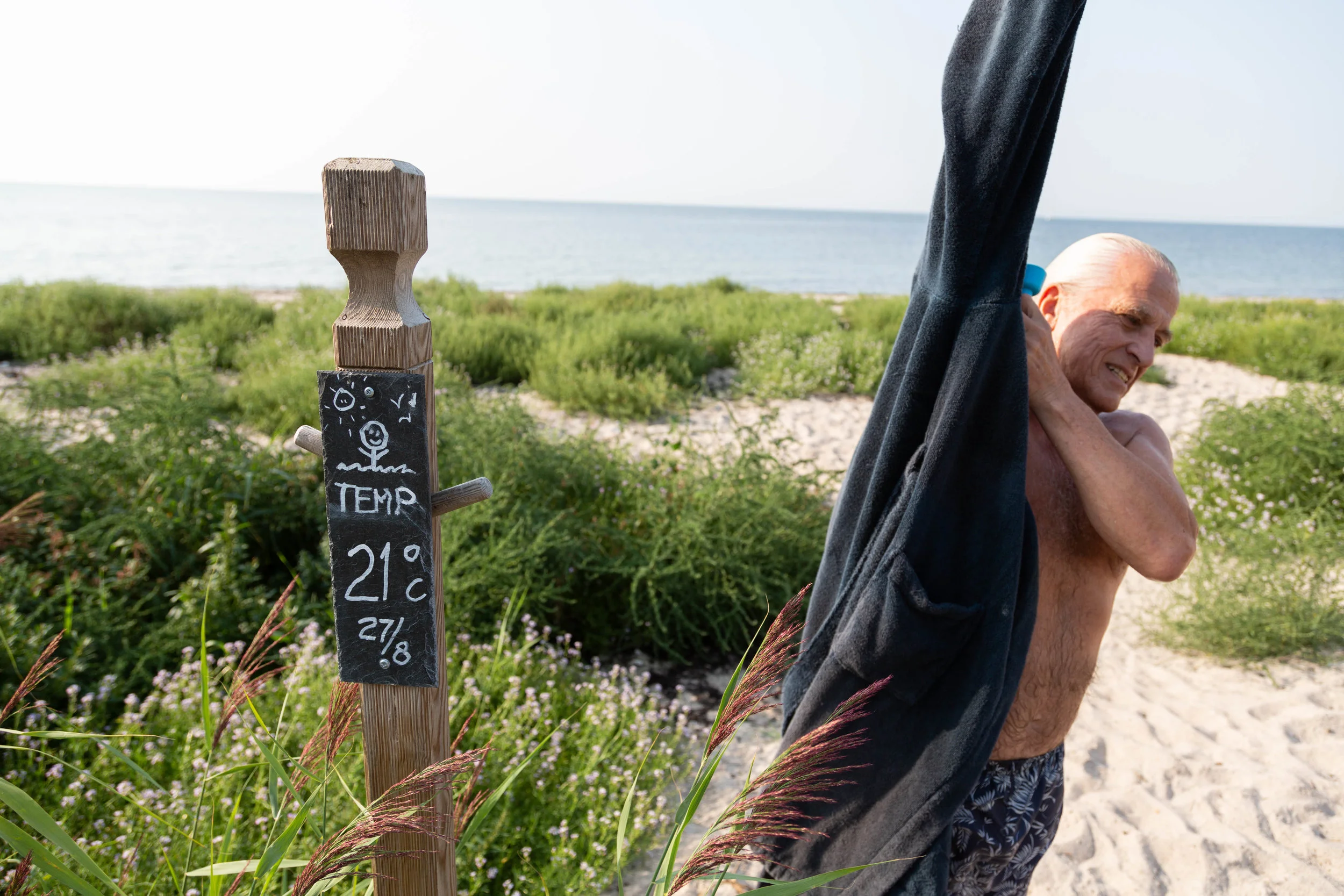 YA:s badkorre Lars Hansson tar temperaturen på badvattnet, augusti 2019. Bilden publicerad i Ystads Allehanda. Foto: Torun Börtz