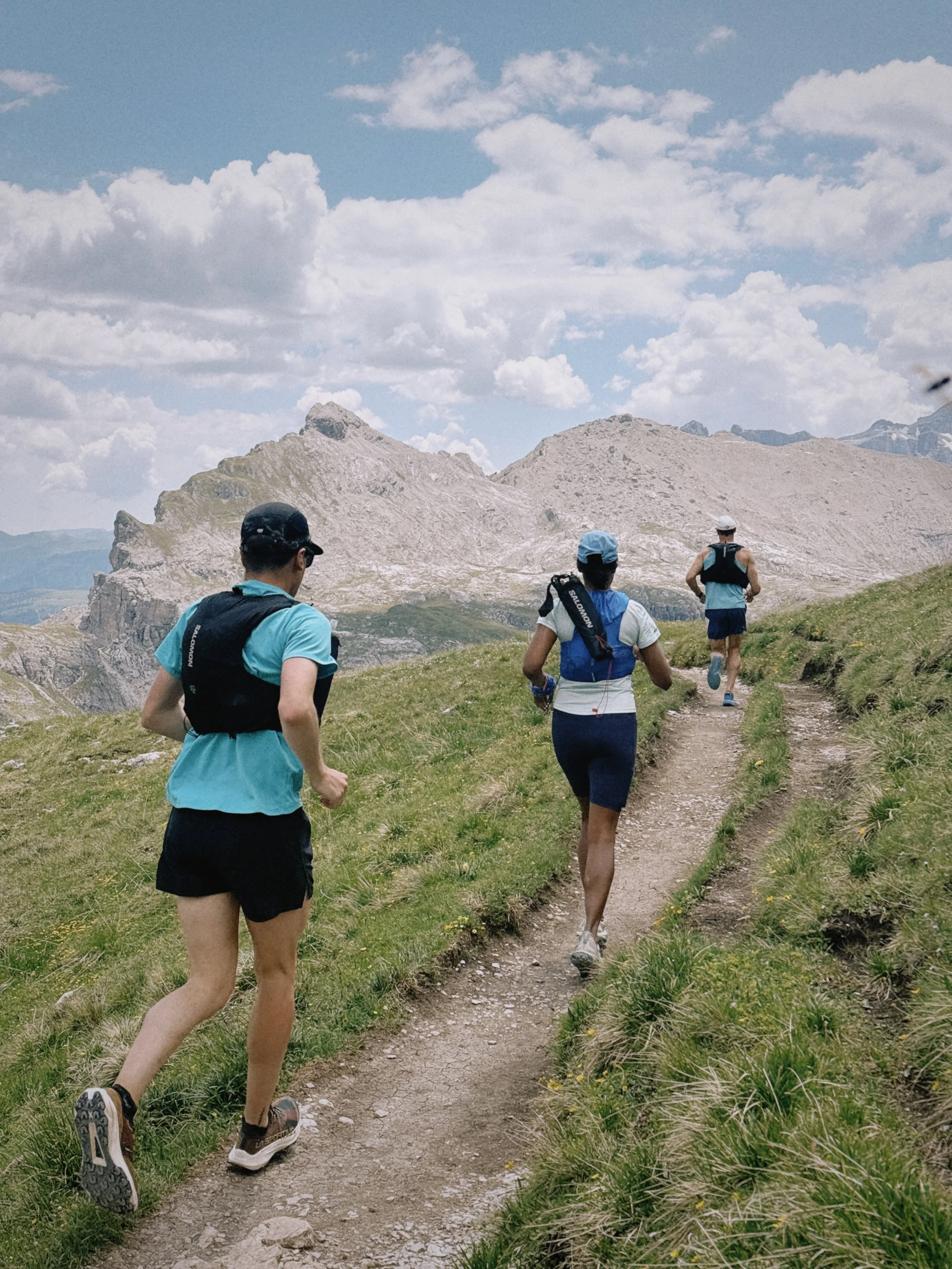 Trail runner on flowy switchback descent through Italian Dolomites singletrack, Puez Odle area overlooking the Vallunga Valley