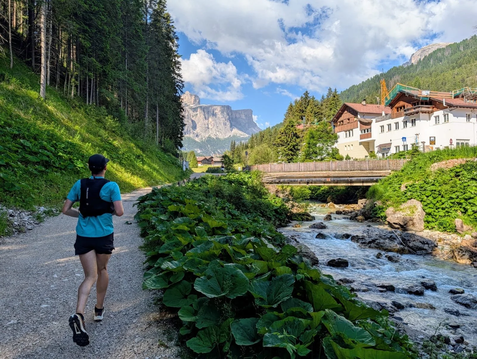 Trail runner along a clear alpine stream beneath Dolomite limestone faces, South Tyrol Italy, Puez Odle Nature Park area