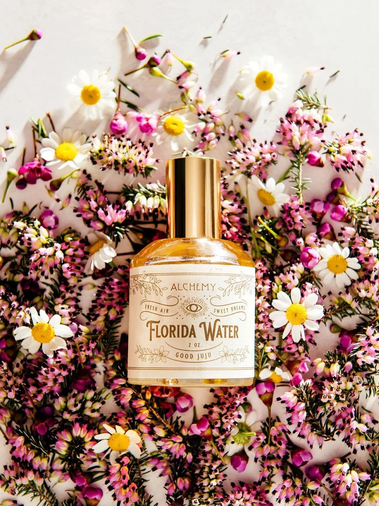 a glass perfume bottle is photographed flat in wax flowers