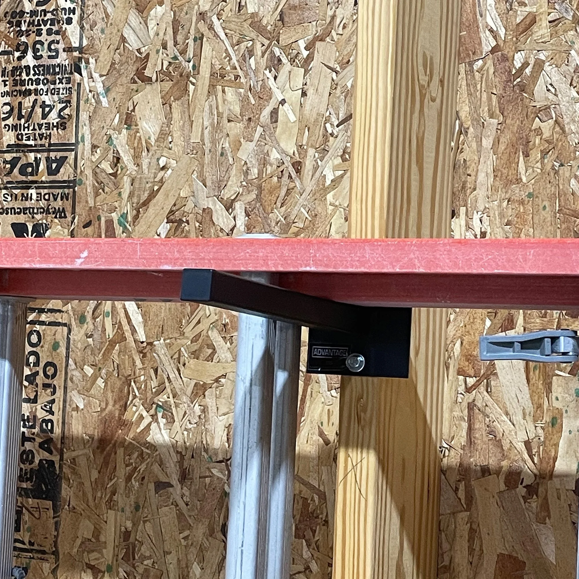 12" Single Prong Tool Rack in black powder-coated steel mounted to a garage wall stud, holding an extension ladder rail — customer install