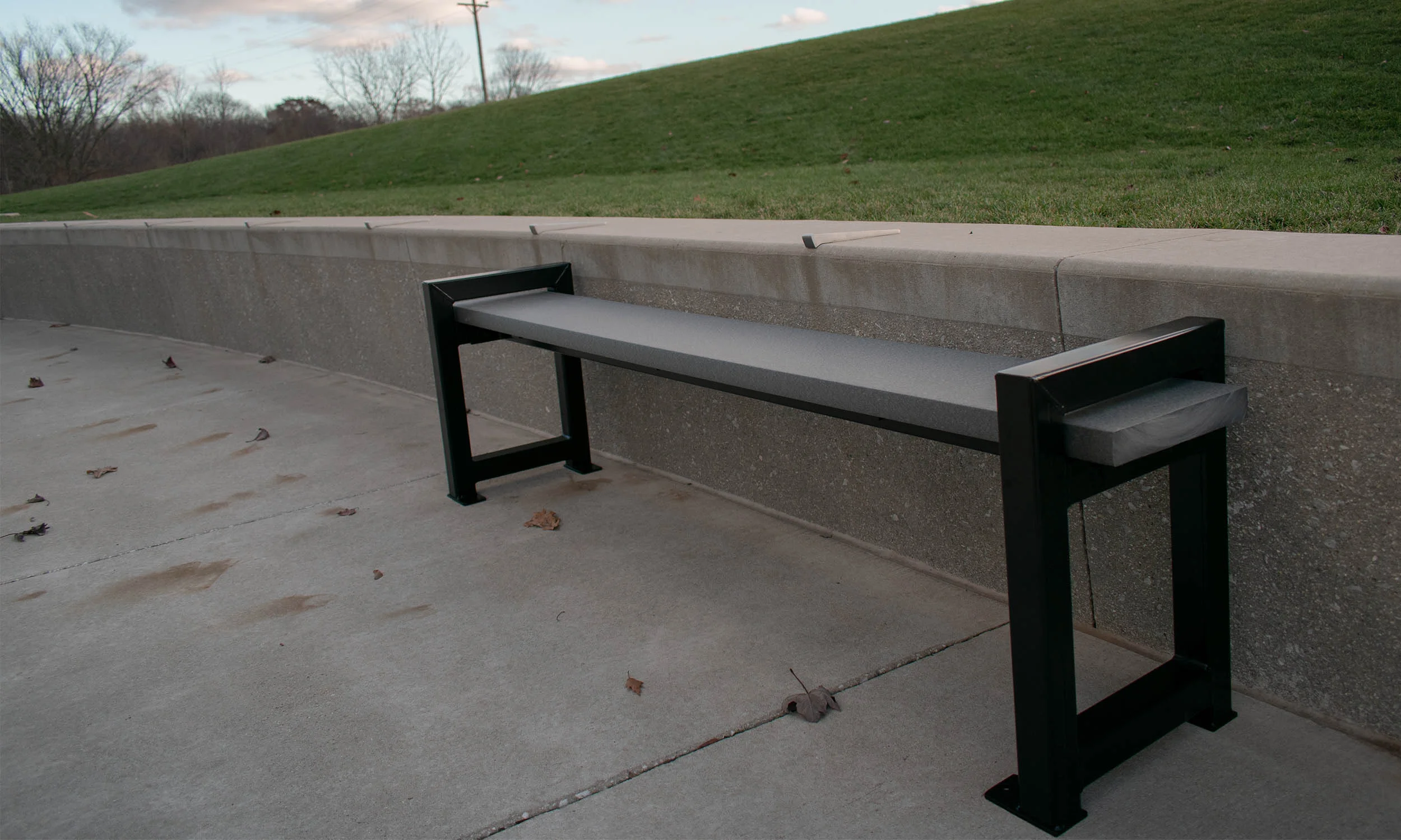 Oswald Park Bench, Dark Grey recycled plastic lumber, backless design with satin black MIG-welded 2" square steel frame, surface-mounted outdoors.